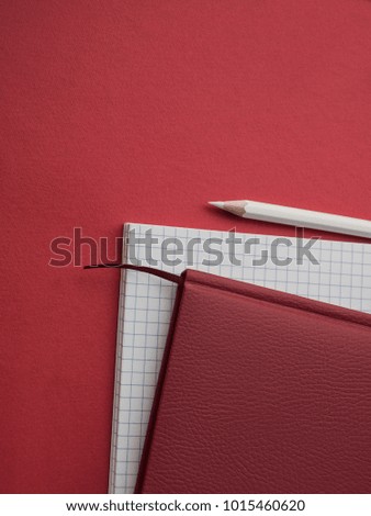 Office accessories: White notepad, red notepad, and white pencil on a red background. Education. Business. The concept. Top view. Copy space.