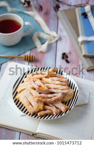 Angel wings pastries, traditional Easter sweet fried pastry from Czech cuisine served with tea and decorated by book and blue cloth.
