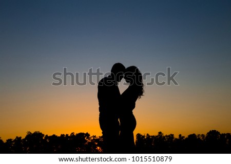 couple in love, a guy and a girl, stand at sunset, hug, love each other, February 14, lovers day, silhouettes in the field