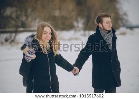 beautiful couple in love walking in the snowy winter woods