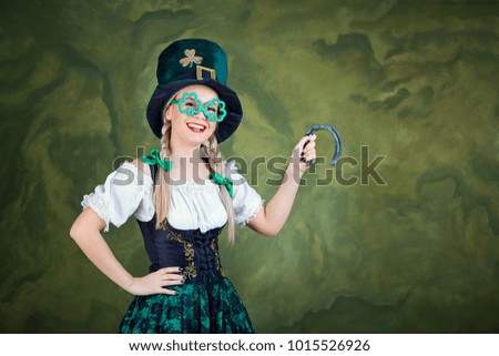 A girl in a St. Patrick costume with a horseshoe in hands.