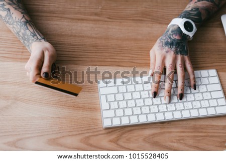 cropped shot of woman with tattoos holding credit card and typing on keyboard