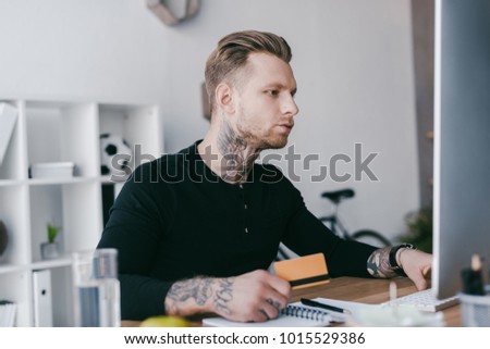 young businessman holding credit card and using desktop computer