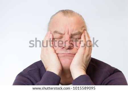 Mature and older man with head in hands and eyes closed resting or asleep. Concept tired or bored.