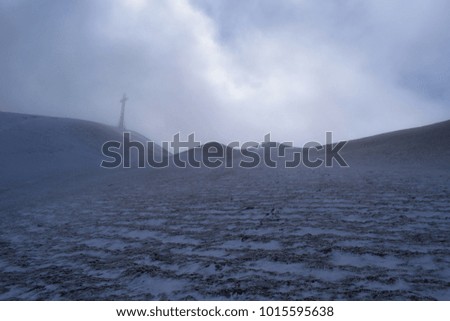 icy metal cross surrounded by clouds on the summit