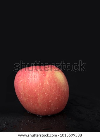 An apple is in front of the black background