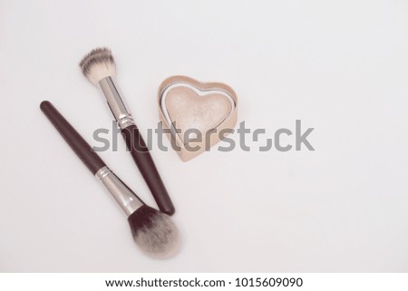 Professional make-up brushes and highlighter in the form of a heart isolated on white background