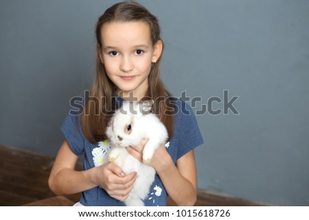 Cute girl is holding a little rabbit in the home.