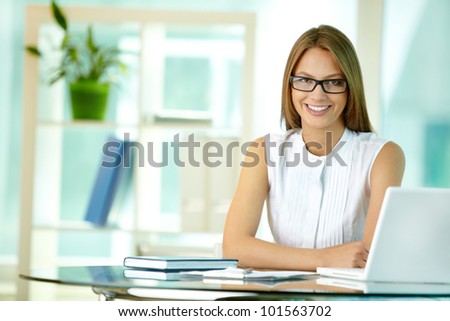 Portrait of a pretty secretary sitting at her desk and smiling Royalty-Free Stock Photo #101563702