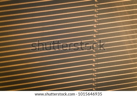 Evening sunlight shining through the blinds casting stripes of light and shadow on the wall.