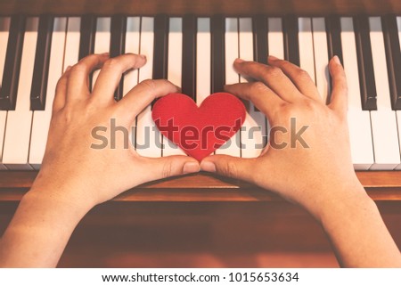 Two hand hold red cartoon heart on keyboard's piano, To tell love to learn music or to tell someone love.
