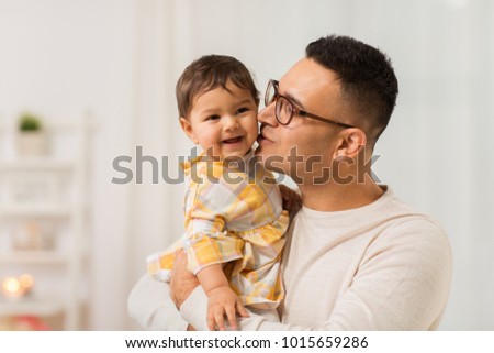 family, fatherhood and people concept - happy father kissing his little baby daughter at home
