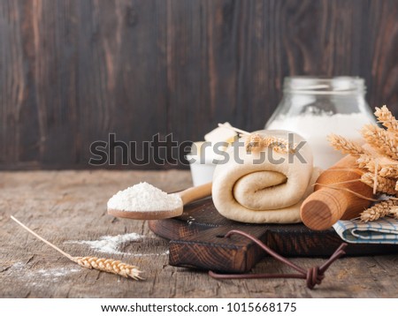 Puff pastry dough. Homemade folded raw puff pastry on a wooden cutting board on a rustic wooden surface (table). Making puff pastry. Dough's rolls with a rolling pin, flour, butter, wheat spikelets. Royalty-Free Stock Photo #1015668175