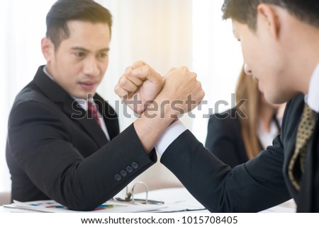 Businessman competing in arm wrestling on the table in office.