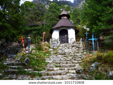 The chapel is white in the mountains around the colorful crosses in the foreground of the steps on the back mountains and forest.