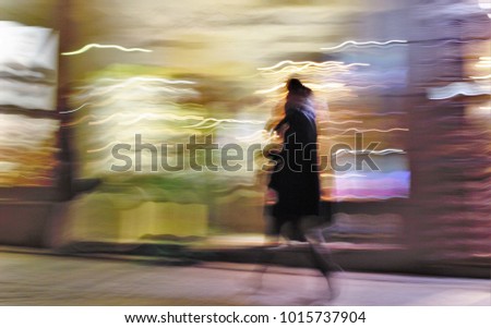 Impressionist night photography of people taken at low speed, in a commercial street, with lights, ghostly shadows, panoramic, blurred background, motion sensation, semi-brutish person,in Toledo,Spain