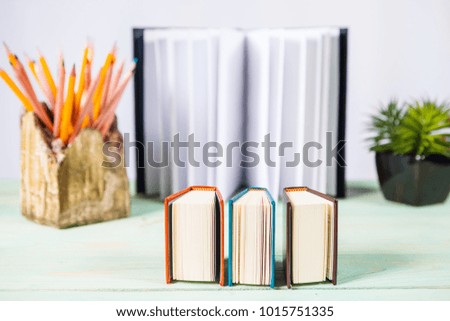 Set of pencils and pile of various books on wooden background. With copy space for your text