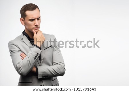 A young man wearing a gray suit thinking. Copy space. Isolated on white. Advertising, fashion and commercial Design,