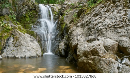 Natural waterfall in dense and wild forest.