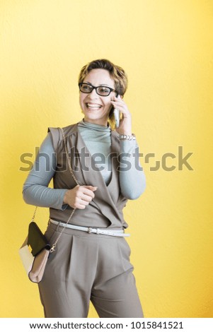 Smiling beautiful woman with mobile phone. Business lady studio portrait on yellow background
