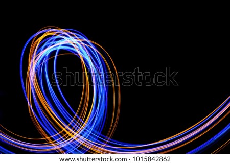 Blue and gold light painting photography, long exposure photo loop, curves and waves against a black background