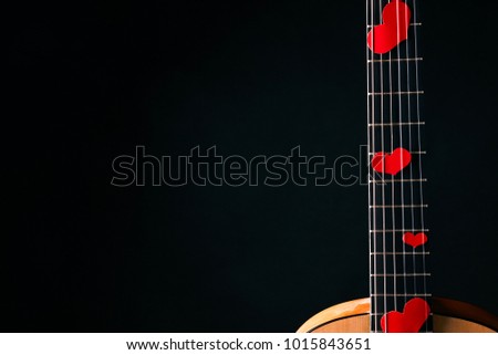 Red hearts on the strings of a guitar