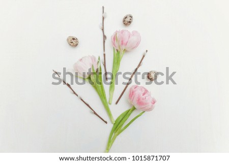 Spring greeting card. Easter eggs with pink tulips and willow branch on white wooden background. Easter concept. Flat lay. Spring flowers tulips