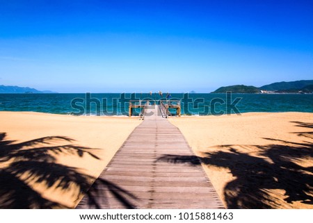 Perspective view of a wooden pier on the tropical seashore with clear blue sky