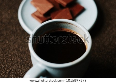 Blue cup of coffee and chocolate on black background. Toned