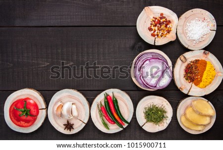 Set of seasonings and spices on wooden brown background with tomato, onion. garlic, pepper. Top view with copy space.