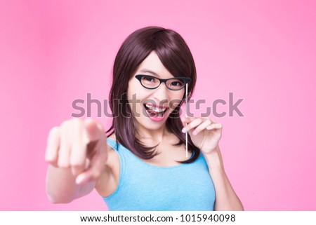woman holding paper party sticks and pointing to you on the pink background
