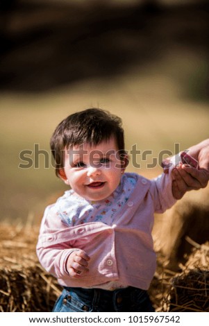 portrait of a baby outdoors holding on to his mother's hand