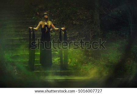 Ð¡lairvoyant. Woman with black ribbon tied in mystical and mysterious forest 
