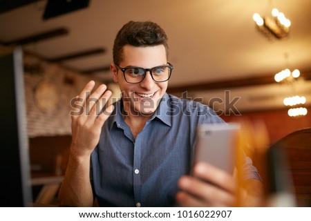 Surprised freelancer hipster man looks to smartphone and can not believe he won lottery prize or money in trading cryptocurrency. Pop-eyed successfull amazed businessman trader. Video call conference Royalty-Free Stock Photo #1016022907