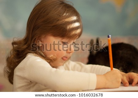 Little girl writing letter to Santa with her best friend bunny