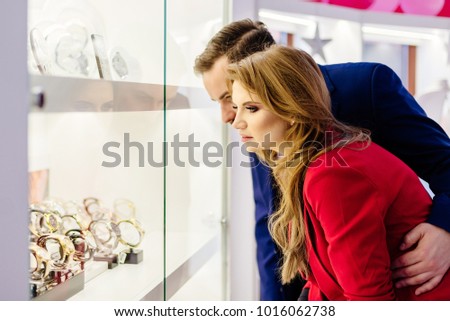 Young elegance couple watching watches on store window in the jewelry store.