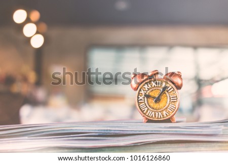Ancient clock and stack of book with warm lighting background