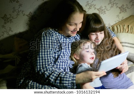 Mother and children with a tablet computer at home watching cartoons and playing