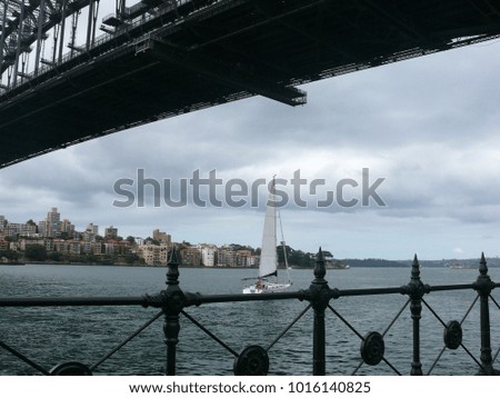 Part from a Steel bridge  before shore with residential houses, and railings and a sailing yacht