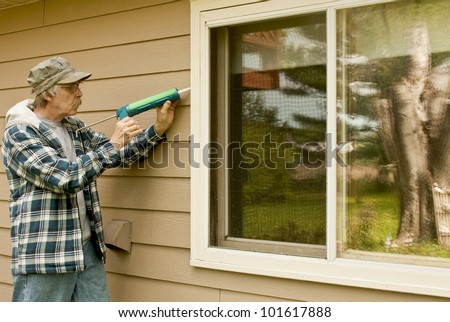 workman sealing an exterior window with caulk to reduce air infiltration Royalty-Free Stock Photo #101617888