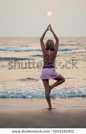 beautiful and young woman practicing meditative yoga on the beach