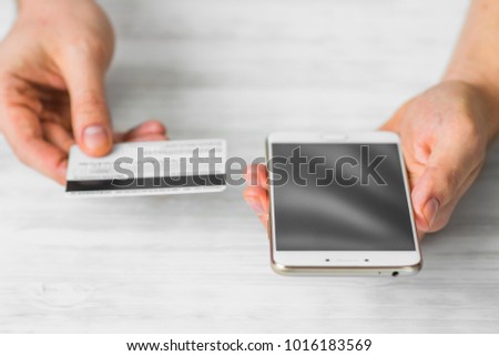 Closeup photo businessman holding hand credit card and using smartphone. Online payments plastic card. Horizontal mockup. Blurred, film effect