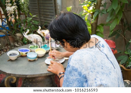 SAMUT SAKHON (THAILAND) Urai Benjarong, An artist decorating a piece of porcelain on a turning table