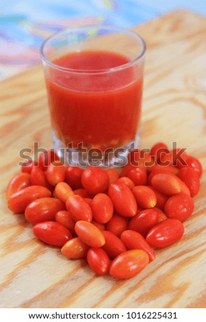 healthy food, cherry tomatoes or baby tomatoes or small tomatoes make heart shape with a glass of tomato juice on wooden table