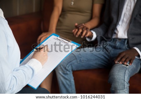 Doctor or psychologist filling medical patient information form holding clipboard consulting african american couple, marriage counseling, family therapy, fertility treatment for infertility concept Royalty-Free Stock Photo #1016244031