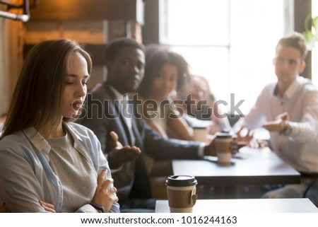 Multiracial friends trying to make peace with insulted girl offended after bad joke, diverse young people apologizing aggrieved resentful drama queen woman sitting apart sulking at meeting in cafe Royalty-Free Stock Photo #1016244163