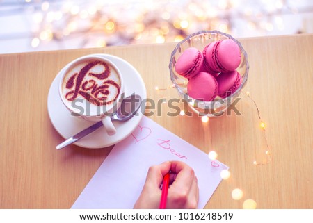 a letter with a confession of love and a cappuccino coffee in a white cup with an inscription made by a love made with cinnamon on air milky foam