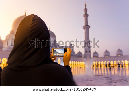 Female tourist taking picture of Sheikh Zayed Grand Mosque by phone