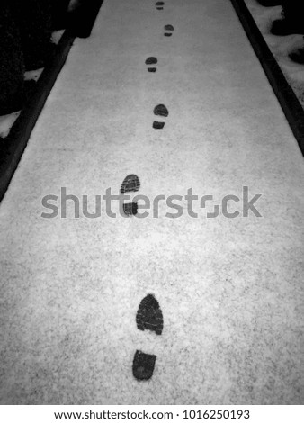 Black and white picture of black footprints on snow path