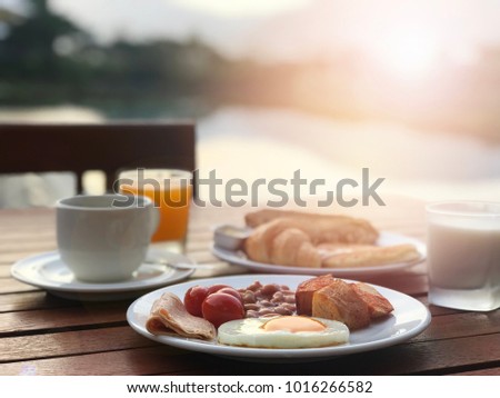 English breakfast with fried egg, bacon, toasts, coffee and orange juice on mountain background in sunshine day    Royalty-Free Stock Photo #1016266582